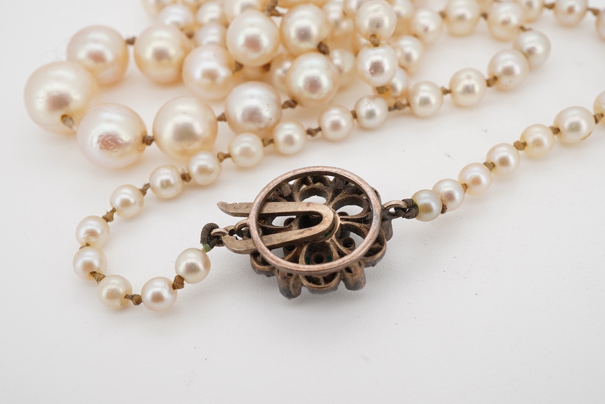 A single strand graduated cultured pearl necklace, with a single stone emerald and rose cut diamond cluster set yellow metal clasp, 64cm.